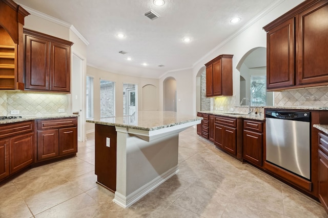 kitchen featuring a breakfast bar area, a center island, light stone countertops, ornamental molding, and stainless steel dishwasher