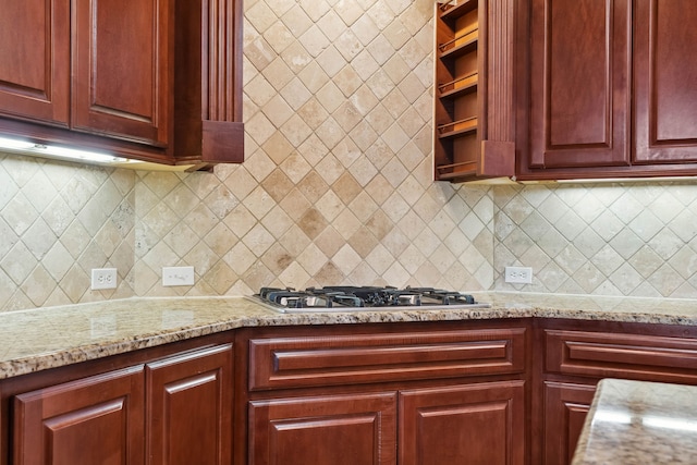 kitchen featuring stainless steel gas stovetop, light stone countertops, and decorative backsplash