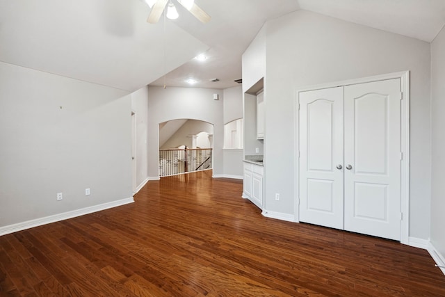 unfurnished living room with vaulted ceiling, dark wood-type flooring, and ceiling fan