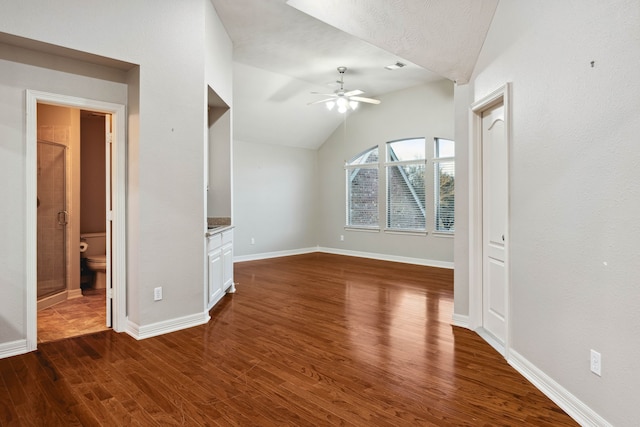 unfurnished living room with dark wood-type flooring, ceiling fan, and vaulted ceiling