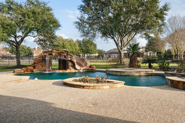 view of swimming pool with pool water feature, a water slide, and a hot tub