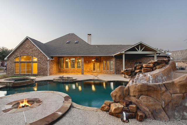 pool at dusk featuring a fire pit, a patio area, and an in ground hot tub