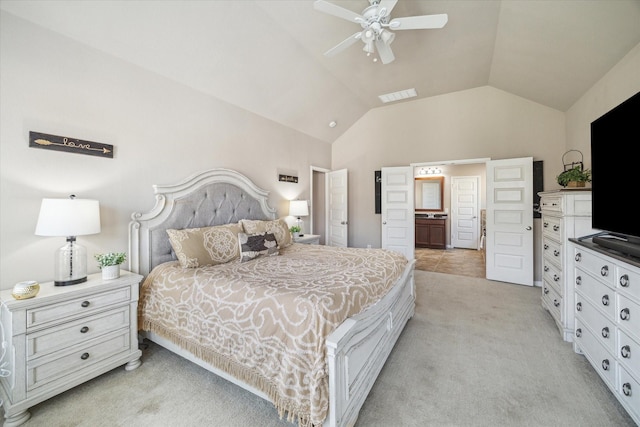 bedroom with lofted ceiling, ensuite bathroom, light colored carpet, and ceiling fan