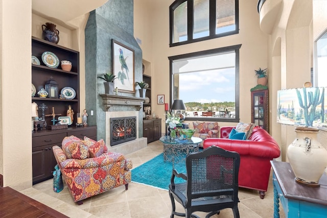 tiled living room with a towering ceiling, a high end fireplace, and built in shelves