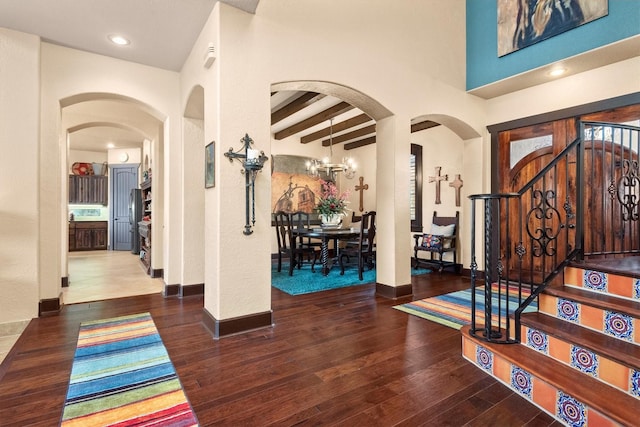 foyer featuring dark hardwood / wood-style flooring, a notable chandelier, beam ceiling, and a high ceiling