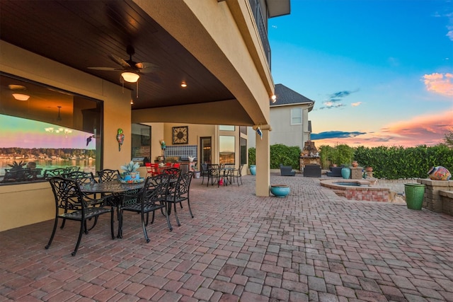 patio terrace at dusk featuring an outdoor fireplace and ceiling fan