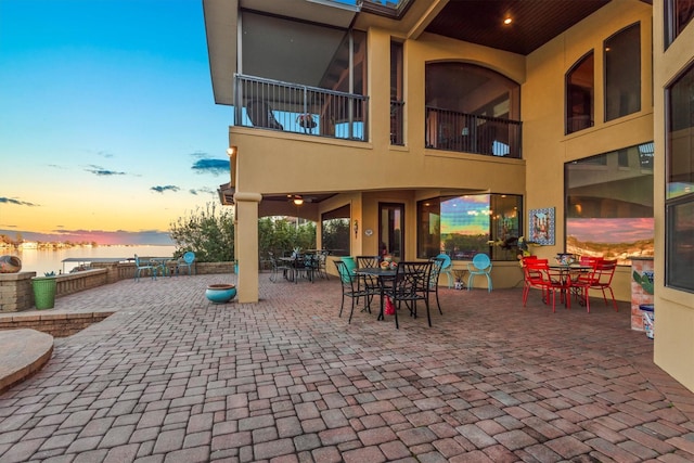 patio terrace at dusk featuring a water view