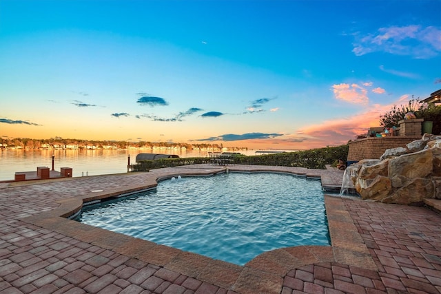 pool at dusk featuring a patio area and a water view