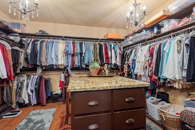 spacious closet featuring light hardwood / wood-style floors and a notable chandelier