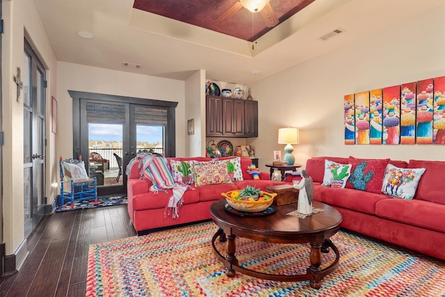 living room with a tray ceiling, dark hardwood / wood-style floors, and french doors