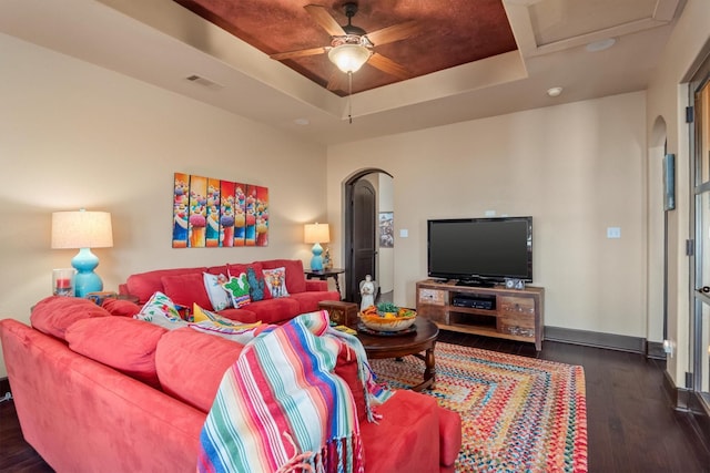 living room with dark wood-type flooring, ceiling fan, and a tray ceiling