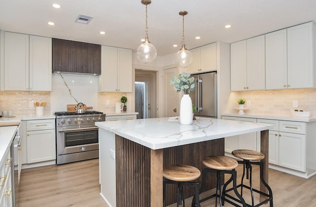 kitchen with white cabinetry, high end appliances, a center island, and extractor fan