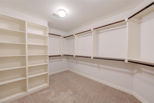 walk in closet with light carpet