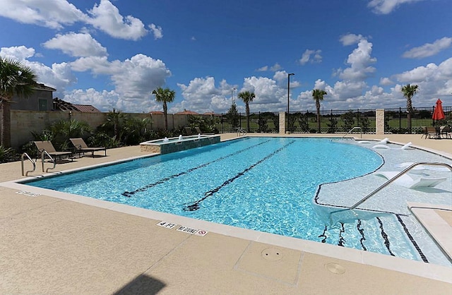 view of pool with a hot tub, pool water feature, and a patio area