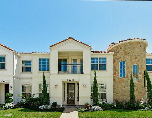 mediterranean / spanish home featuring a front lawn and a balcony