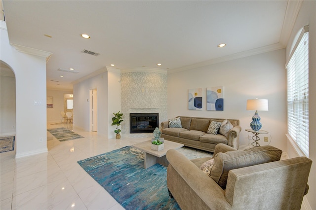 living room with ornamental molding, plenty of natural light, and a large fireplace