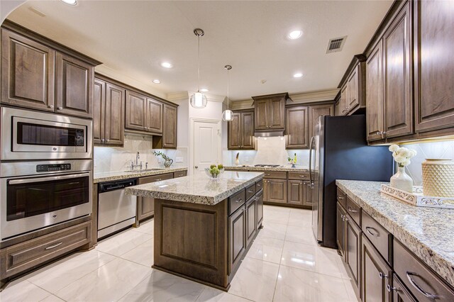 kitchen with dark brown cabinetry, hanging light fixtures, stainless steel appliances, and a kitchen island