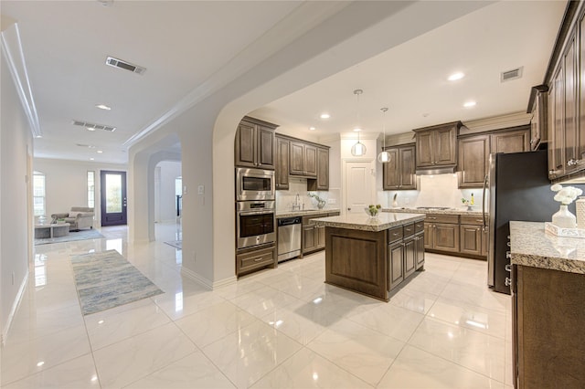 kitchen featuring a kitchen island, appliances with stainless steel finishes, tasteful backsplash, hanging light fixtures, and crown molding