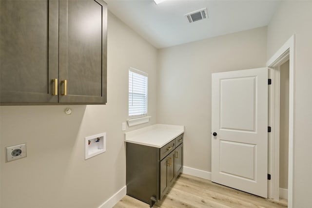 clothes washing area featuring cabinets, hookup for a washing machine, hookup for an electric dryer, and light hardwood / wood-style flooring