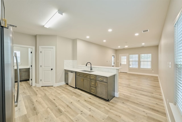 kitchen with sink, appliances with stainless steel finishes, dark brown cabinetry, light hardwood / wood-style floors, and kitchen peninsula