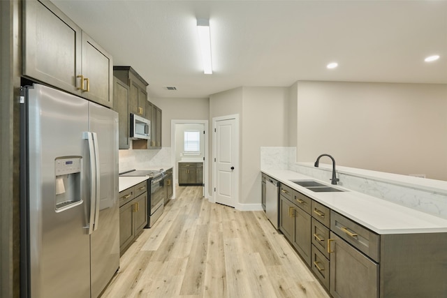 kitchen featuring sink, dark brown cabinets, stainless steel appliances, light hardwood / wood-style floors, and decorative backsplash