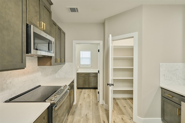 kitchen with backsplash, dark brown cabinets, stainless steel appliances, and light wood-type flooring