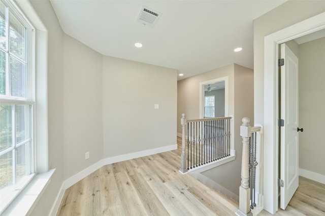 corridor featuring a healthy amount of sunlight and light hardwood / wood-style floors