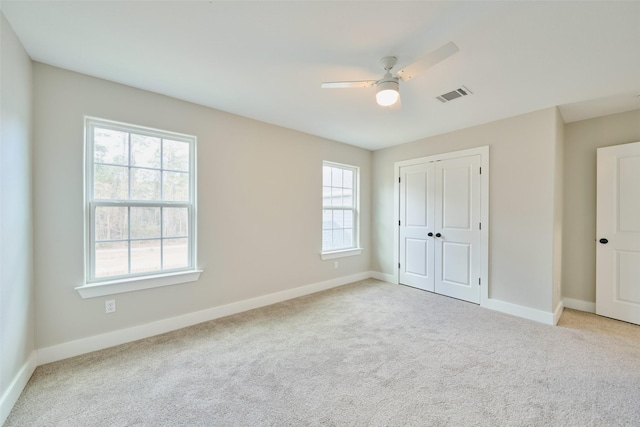 unfurnished bedroom featuring light carpet, a closet, and ceiling fan