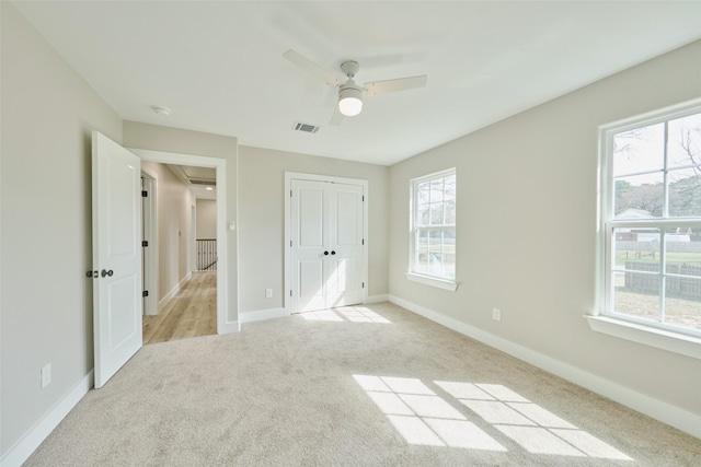 unfurnished bedroom featuring ceiling fan, a closet, and light carpet