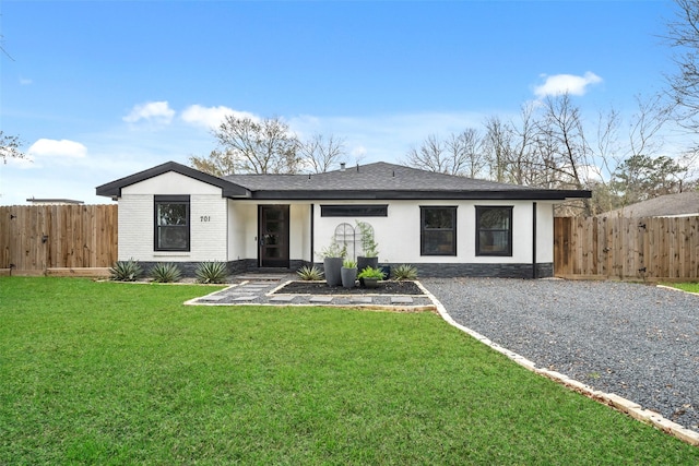 view of front of property with a front yard, brick siding, and fence