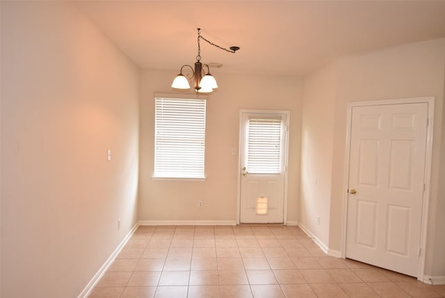 empty room featuring light tile patterned floors and a chandelier