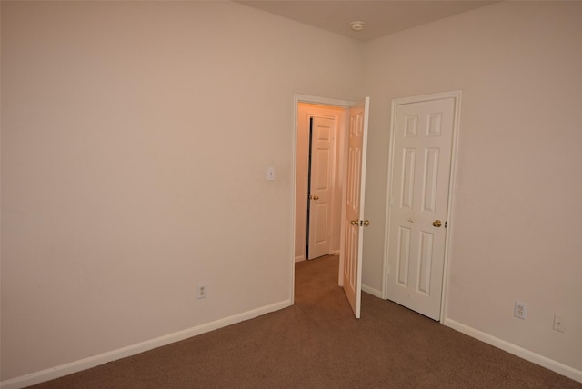 unfurnished room featuring dark carpet