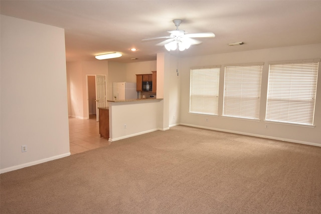 unfurnished living room featuring light carpet and ceiling fan