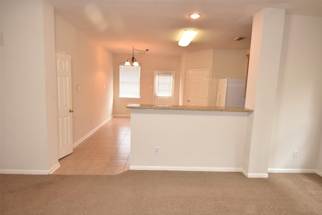 kitchen with hanging light fixtures, white fridge, light carpet, and kitchen peninsula