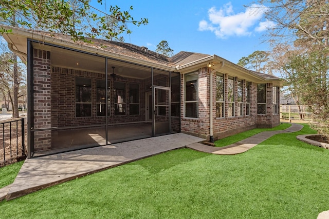 back of property featuring a sunroom, a patio, and a lawn