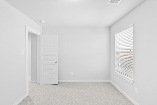 empty room featuring baseboards, visible vents, and light colored carpet