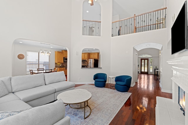 living room featuring a tiled fireplace, dark hardwood / wood-style floors, and a notable chandelier