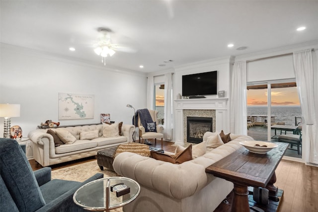 living room with hardwood / wood-style floors, crown molding, recessed lighting, and a glass covered fireplace