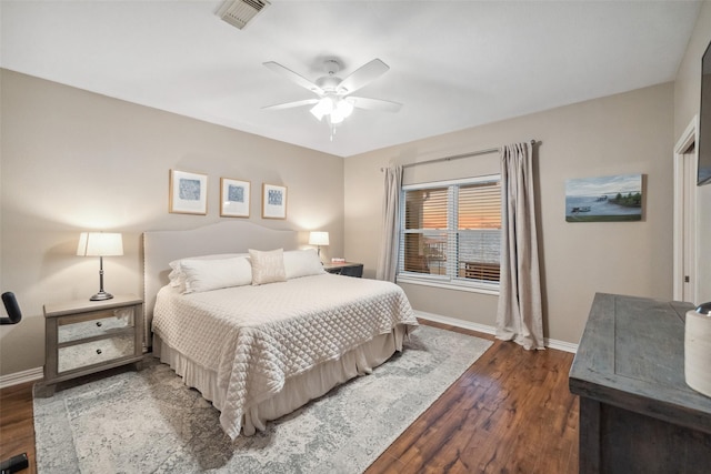 bedroom with ceiling fan, wood finished floors, visible vents, and baseboards