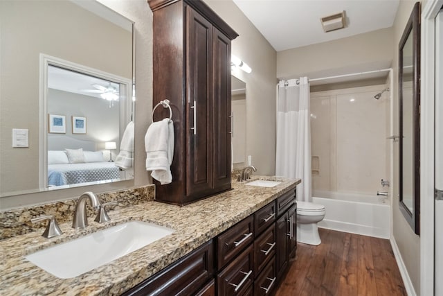 bathroom featuring connected bathroom, wood finished floors, toilet, and a sink