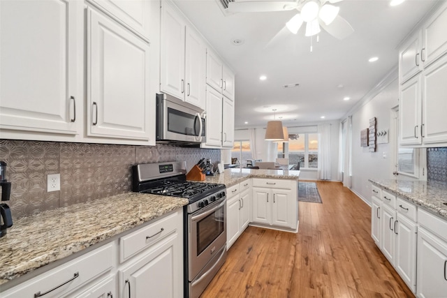 kitchen featuring stainless steel appliances, backsplash, a peninsula, and white cabinets