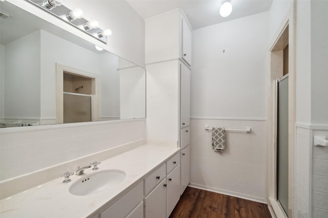 full bathroom featuring a wainscoted wall, a shower stall, visible vents, and wood finished floors