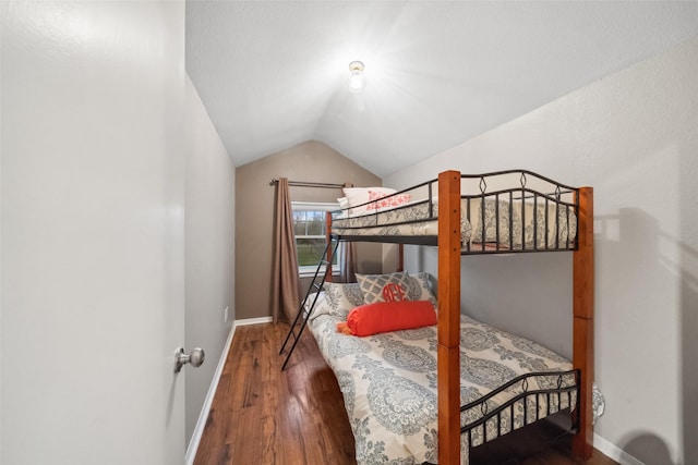 bedroom featuring lofted ceiling, wood finished floors, and baseboards