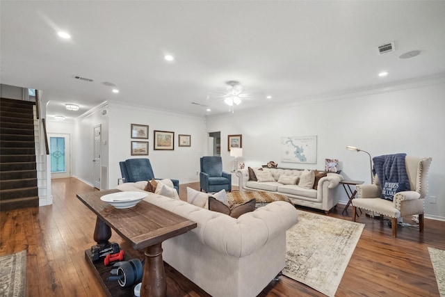 living room featuring crown molding, stairway, visible vents, and wood-type flooring