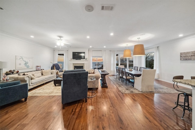 living room featuring crown molding, hardwood / wood-style flooring, a fireplace, and visible vents