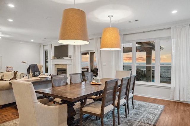 dining room with visible vents, crown molding, a tiled fireplace, recessed lighting, and wood finished floors
