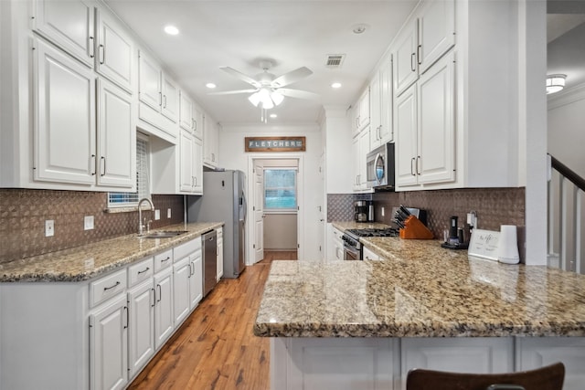 kitchen featuring a sink, a peninsula, white cabinets, and stainless steel appliances