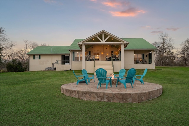 rear view of house with a yard, a balcony, metal roof, and a patio area