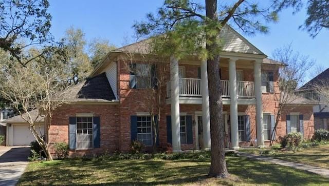 greek revival inspired property featuring a balcony and a front lawn