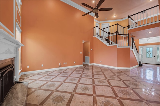 unfurnished living room with ornamental molding, a towering ceiling, and ceiling fan